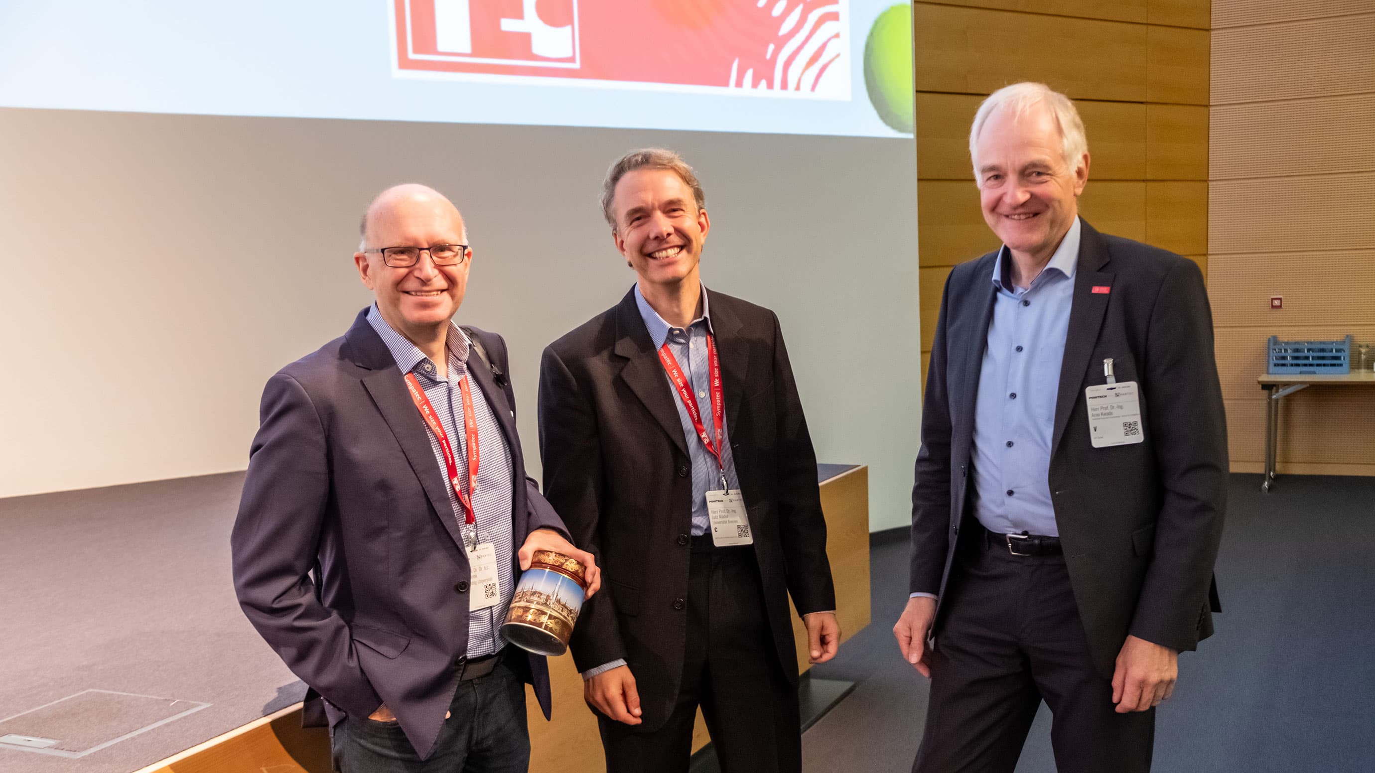Three men in front of the stage smiling